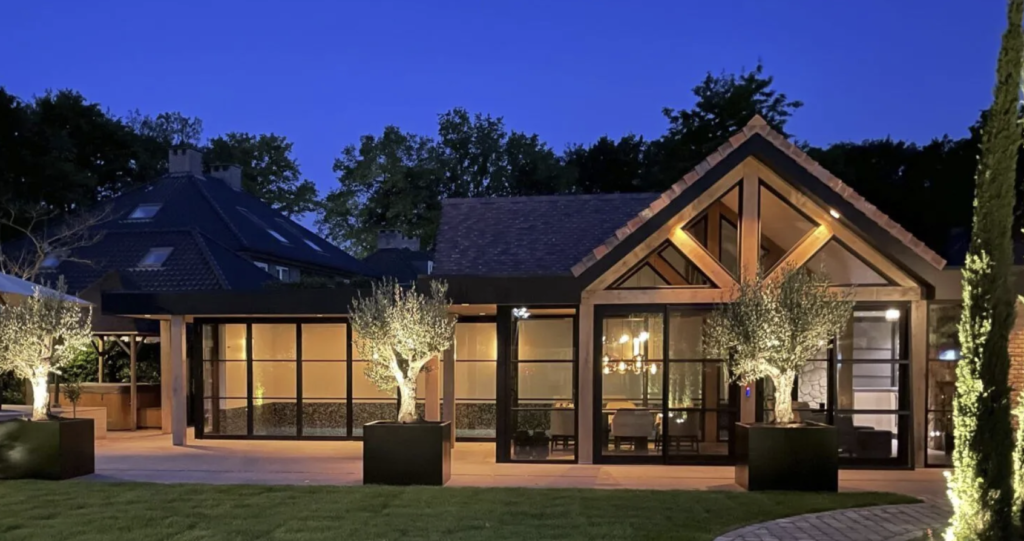 Eiken tuinkamer met glazen puien en sfeerverlichting in een moderne tuin in de avond